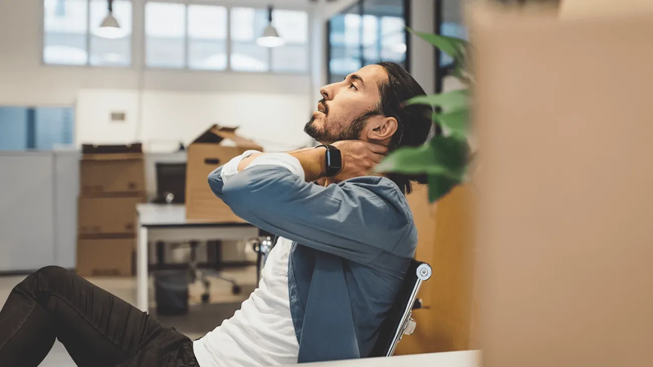 A man pensively looking upwards while leaning back in a chair.